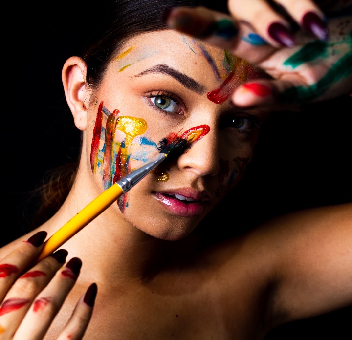 Retrato artístico de mulher com tintas coloridas no rosto